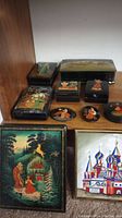 Photo showing the full set of 10 Russian hand-painted lidded boxes with various sizes and detailed folk art scenes on tops.