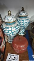 Photo of two blue floral lidded urns and one red metal apple container, showing overall size and design.