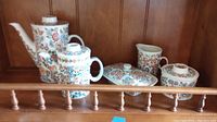 Wide view of all floral patterned ceramic items on shelf, showing two teapots, creamer, sugar bowl, and butter dish.