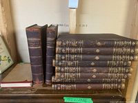 Antique leather-bound books arranged on a shelf with visible spines showing titles and volume numbers