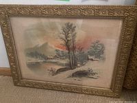 Full view of framed chromolithograph showing winter landscape with stone bridge, trees, houses, and mountains with sunset sky.
