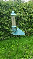Full view of the bird feeder attached to the shepherd's hook and visible squirrel baffle cone attached below the feeder perch.