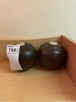 Two vintage lawn bowling balls on a wooden surface, showing the circular WBS label and engraved lines