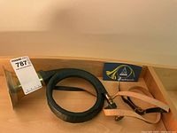 Full view of bugle coiled with black leather covering, leather strap, and music book in wooden tray