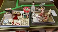 Top view of trays displaying a variety of Christmas angel ornaments and decorations including a boxed porcelain bell, stained glass angel ornament, ceramic and porcelain figurines.