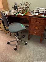 Full view of wood desk with privacy panel, three drawers on the right, slide-out work surface, and adjustable office chair.