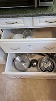 Drawer with stainless steel pots, frying pan, mixing bowls stacked