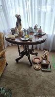 Full table with multiple decorative items on top and some items on the floor next to it. Items not included in the lot per description.