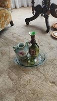 Three vases and glass serving tray on carpet floor near wood furniture
