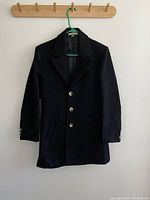 Black Montmartre jacket with silver buttons hanging on wooden rack