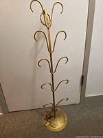 Full view of the brass shoe rack standing upright with multiple curved hooks.