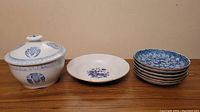 Photo showing the full ceramic set: six small floral design plates, one porcelain ginseng bowl, and one decorative serving bowl with lid.