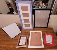 Display of six photo frames on a table showing size and variety including multi-slot and IKEA NYTTJA frames