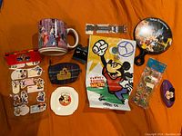 Assorted Disney mugs, plates, pins, stickers, a Mickey wristband and a Tokyo Disneyland souvenir plate