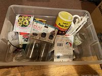 Plastic bin with seed packets (sunflower, wildflowers), peat pellets, bulb dust container, plant labels, and a glass jar.