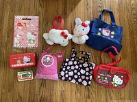Photo showing Hello Kitty and Sanrio plush toys, pouches, bags, and pencil case items arranged on wood floor