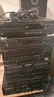 Stacked Kenwood stereo components showing CD player, radio tuner, amplifier, and equalizer.