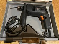 Black & Decker BD552 corded drill with side handle and drill bit attached inside a case.