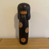 Full front view of the 12-inch Japanese Kokeshi doll with black body and orange floral designs.