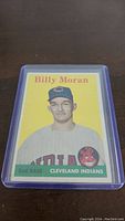 Front view of 1958 Topps Billy Moran Rookie baseball card showing portrait with yellow background and team logo in protective sleeve.