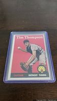Front view of 1958 Topps Tim Thompson rookie card in plastic sleeve with red background and player image.