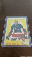 Front side of the 1959-1960 Topps John Hanna hockey card showing player portrait with New York Rangers uniform and yellow border.