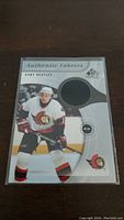 Front of Dany Heatley jersey card showing player image and embedded jersey fabric swatch.