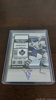 Front view of Korbinian Holzer rookie hockey card with autograph and player in Toronto Maple Leafs uniform, number 155