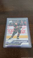 Front of Maxence Guenette Young Guns rookie card in protective plastic sleeve showing player in action skating with Ottawa Senators uniform and Young Guns branding