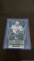Front photo of Quinn Hughes hockey rookie card showing him in Vancouver Canucks gear with Millennial Impact branding.
