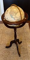 Full view of the spinning globe on a wooden frame standing on a carpeted floor.