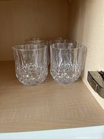 Six crystal old fashioned glasses displayed in two rows inside a cabinet.