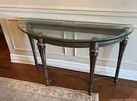 Front angled view of the glass and metal semi-circular hall table showing the glass top, metal legs, and frame details.