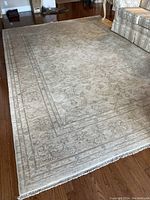 Full view of rug laid out on hardwood floor showing overall pattern and fringed edges.