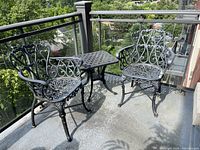 Overview of two cast metal chairs and lattice-top table on balcony