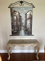 Front view of the wooden sofa table with glass panel inserts and wall art above it.