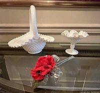 Image showing the white hobnail handled basket with scalloped ruffled rim next to the candy dish on a table with a red flower decoration.