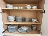 Noritatake china set organized on shelving showing plates and bowls with floral pattern and scalloped edges