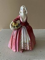 Front view of the Royal Doulton porcelain figurine Janet showing detailed dress and flower basket.