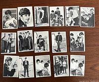 Front view of 16 black and white Beatles bubblegum cards laid out on table.