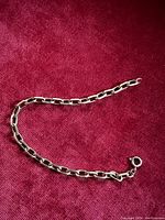 Full view of Birks gold link bracelet laid flat on red fabric background