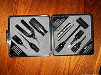 Open black case showing various small hand tools fixed in foam inserts.