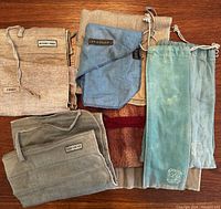 Six assorted felt cutlery holders arranged on a wooden surface, showing labels and colors.