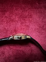 Side profile of watch showing gold-tone case and leather strap attachment