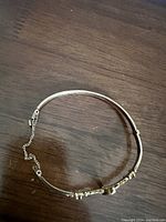 Full view of the gold bangle bracelet laid flat on wood surface.