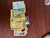 Pile of assorted vintage Pokemon trading cards from 1996-1998, cards include water and psychic types and trainer cards, showing used condition.