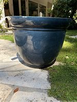 Side view of the large black plastic plant pot showing its height and shape on outdoor stone patio.