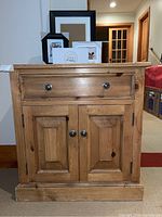 Front view of solid pine media cabinet with a drawer and double doors below, placed indoors with frames on top.