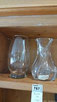 Both vases displayed together on wooden shelf, showing relative size and clear crystal and glass materials.