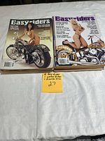 Photo showing a stack of 17 Easy Rider magazines with covers featuring custom motorcycles and models, laid on a white cloth background with a sticky note indicating '15 Easy Rider + 2 more'.